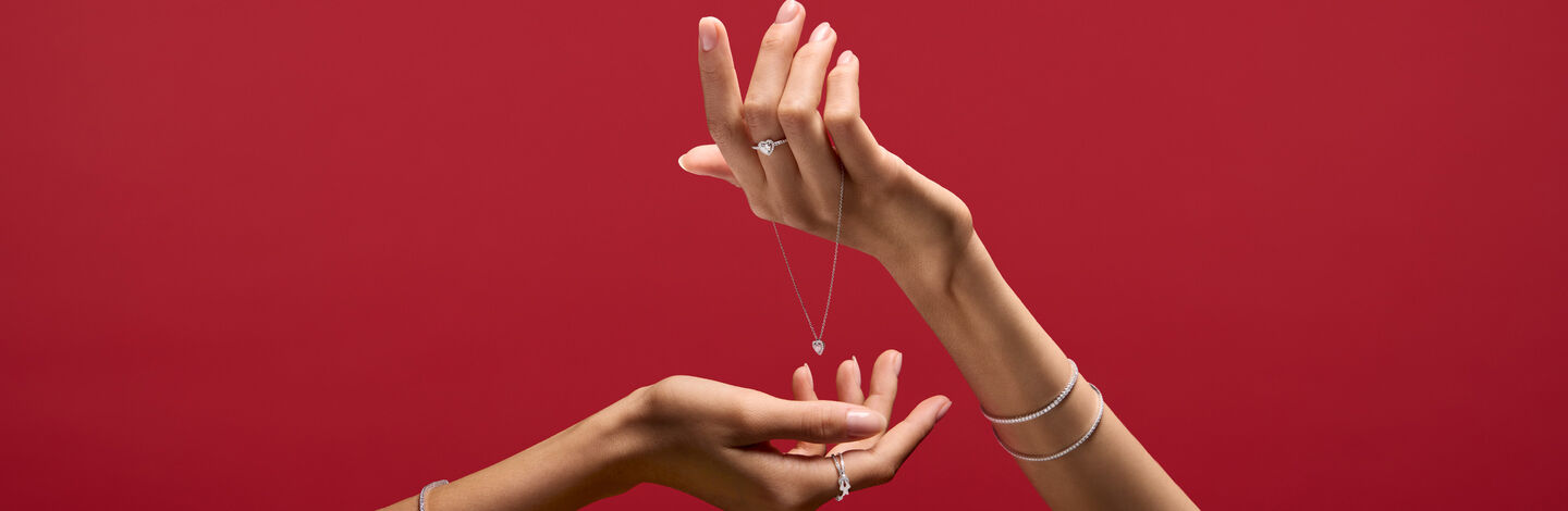 A woman holding Maison Birks jewellery on red background.